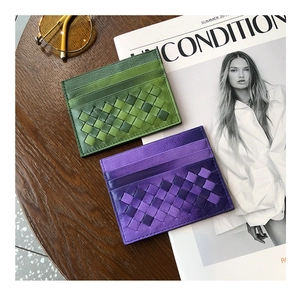 Flat lay of woven sheepskin card holders in green and purple on a wooden table