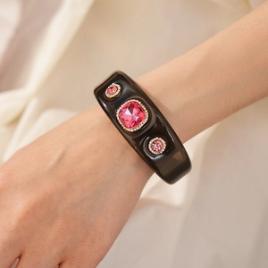 Detail of vintage resin cuff bracelet featuring a large square pink gemstone and side crystals