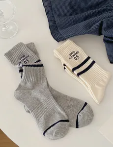 Close-up of striped cotton crew socks with letter embroidery in grey and beige tones