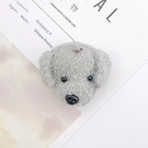 Close-up of a grey curly plush puppy pendant with lamb wool texture and black eyes