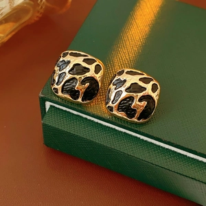 Boucles d'oreilles carrées léopard présentées sur un écrin à bijoux en cuir vert