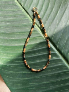 Detail of bohemian handmade beaded necklace on green leaf with tiger eye stones