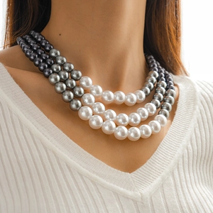 Detailed view of layered faux pearl necklace with grey and white gradient beads on model