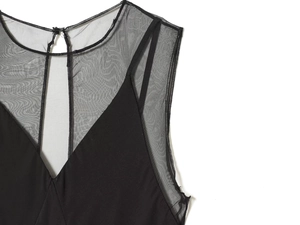 Detail of elegant black dress showing V-neckline and sheer mesh patchwork on shoulders