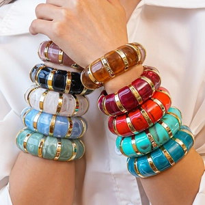 Close-up of colorful resin acrylic bangle stack with gold dividers on model wrist