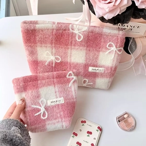Detail showing two sizes of pink checkered plush makeup bags with 3D white bow tie accents