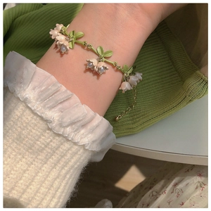 Pastel lily of the valley bracelet with pearls and green leaves on a feminine wrist