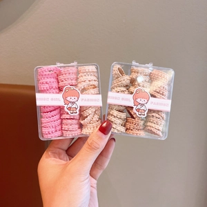 Close-up of pink and beige wavy elastic hair ties in two transparent storage boxes