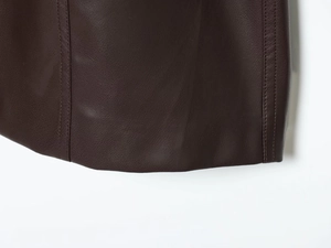 Macro shot of double-stitched hem on dark brown PU leather dress with fine texture