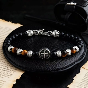 Macro shot of 6mm black beads and brown tiger eye stone bracelet with a cross metal charm