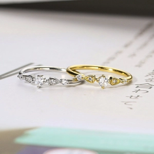 Set of two minimalist gold and silver rings with cubic zirconia on a magazine