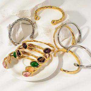 Minimalist 18K gold and silver teardrop open bangles set on stone and porcelain