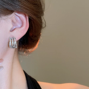 Close-up of silver-tone multi-layer crisscross earrings with pave-set shimmering zircons