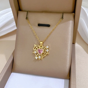 Detail of gold spider web pendant with pink heart gemstone and sparkling zircons