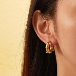 Macro detail of 18k gold plated C-shaped earrings with pearls and cubic zirconia