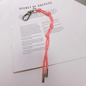 Détail d'un porte-clés en corde tressée rose avec fermoirs métalliques sur un magazine