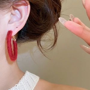 Detailed view of large red flocked hoop earrings worn by a model for daily styling
