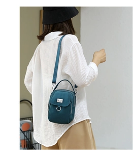 Navy blue nylon crossbody bag on model featuring wide strap and multi-compartment design