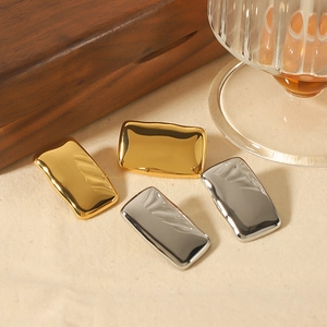 Polished 18K gold and silver geometric stainless steel earrings on a textured fabric