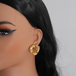 Close-up of golden irregular textured hoop earring on model with metallic foil surface