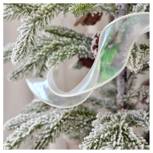 Close-up of holographic translucent ribbon with mesh texture on a snowy Christmas tree branch
