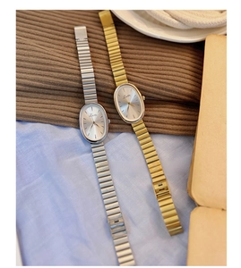 Macro shot of vintage oval quartz watch with elegant metallic link band on soft fabric