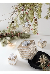 Detailed view of champagne gold glitter Christmas box ornaments with white silk bows