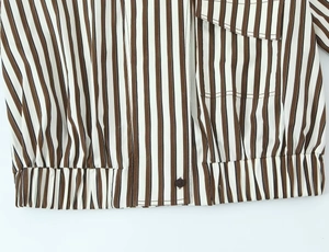 Détail d'une chemise rayée avec ourlet élastique, boutons bruns et poche carrée