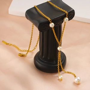 Elegant long gold chain pearl necklace with fringe tassel on a decorative column stand