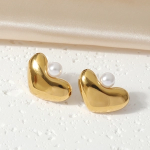 Elegant gold heart earrings with white pearls on a soft champagne silk backdrop