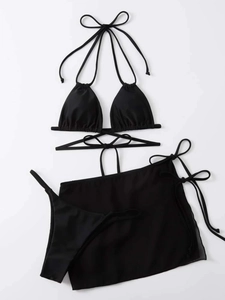 Detailed flat lay of black three-piece bikini set with sheer mesh sarong and side ties