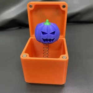 Vista dettagliata di una scatola a sorpresa arancione 3D con testa di zucca viola su molla