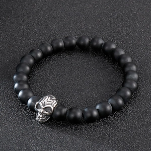 Detail of matte black beads and vintage silver skull pendant on men's punk bracelet