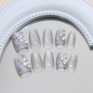 Grey cat-eye press-on nails with purple leaf design and marquise rhinestones on mirror