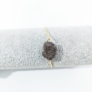 Detail of a natural smoky crystal stone on a delicate gold adjustable chain bracelet