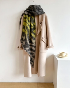 Détail d'une écharpe léopard à franges avec un manteau beige sur fond de studio photo