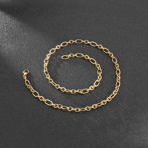 Detailed close-up of golden Figaro chain link necklace with polished stainless steel finish