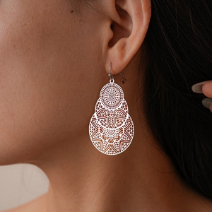 Gros plan de boucles d'oreilles mandala en argent avec un motif floral géométrique triple