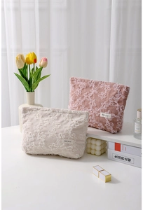 Detail of corduroy makeup bag with delicate lace floral embroidery and brand label