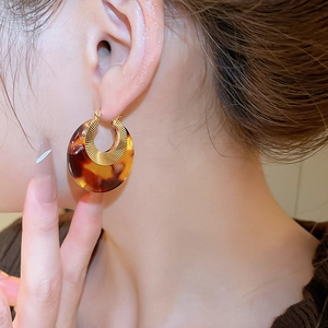 Detail of tortoiseshell acetate hoop earrings with internal golden sunburst metal texture