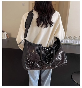 Bolso de viaje con lentejuelas negras y correas de cuero PU mostrado por una modelo