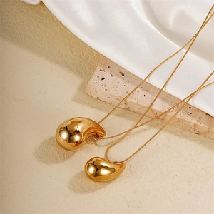 Minimalist gold teardrop pendant necklace in polished titanium steel on white silk