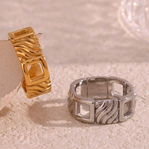 Close-up of gold and silver square hollow rings with diagonal texture on beige background