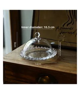 Detail of clear glass cloche with beaded edge base on a wooden cabinet, 14cm diameter