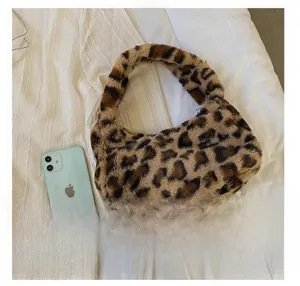 Detail view of plush leopard print handbag with a phone for scale on white fabric
