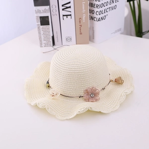 Detail of beige straw hat featuring a pink silk flower and elegant pearl bead ribbon