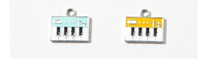 Detail of blue and yellow enamel piano charms with white keys and metal rings