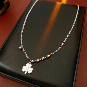 Detailed view of silver clover pendant with 520 engraving and decorative beads