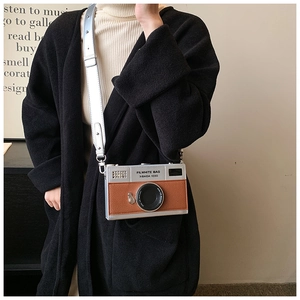 Detail of vintage-style mini camera box bag with silver shoulder strap on model
