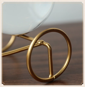 Detail of golden metal tricycle stand holding a clear crystal ball home decoration